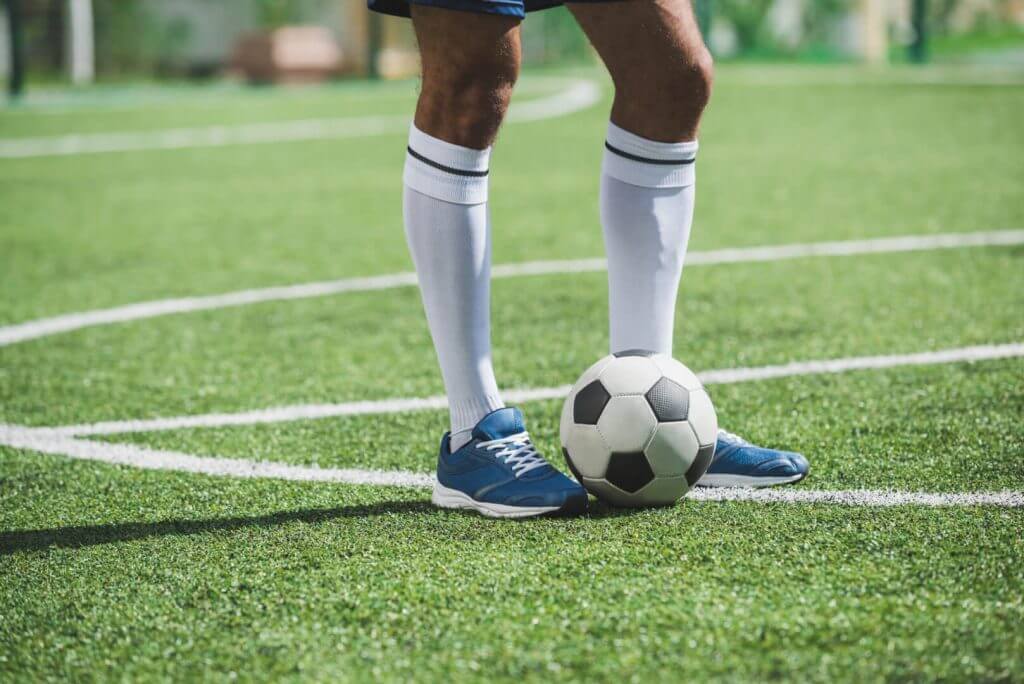 soccer player standing on pitch with ball
