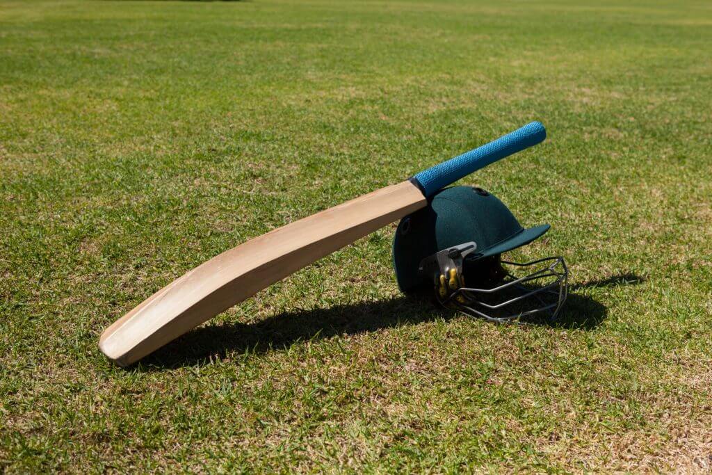 Cricket bat and helmet on field during sunny day