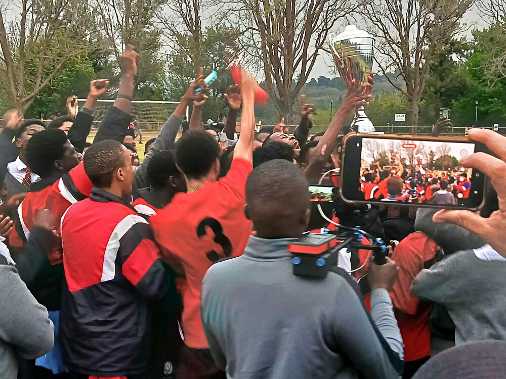Maritzburg College captain KG Matshoge hoists the Cowie Cup, surrounded by the Red, Black and White's supporters. Photo: Brad Morgan.