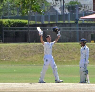 Cayden Wilson raises his bat and helmet in triumph and to acknowledge the applause after he reached a century against St Alban's College. Photo: Pearson High School Official on Instagram.