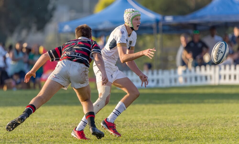St Charles flyhalf AJ Bosman passes as Maritzburg College hooker Theo Boshoff lines up a tackle on the number 10. Photo: Justin Waldman Sports Photography.
